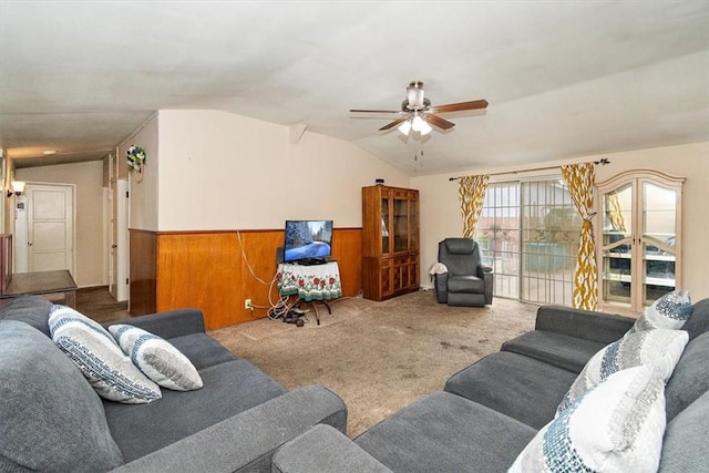 living room with carpet floors, vaulted ceiling, wood walls, and ceiling fan