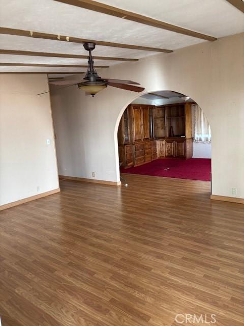 interior space with ceiling fan, dark hardwood / wood-style flooring, and beam ceiling