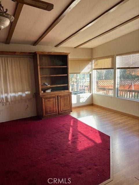 unfurnished living room with vaulted ceiling with beams and hardwood / wood-style floors