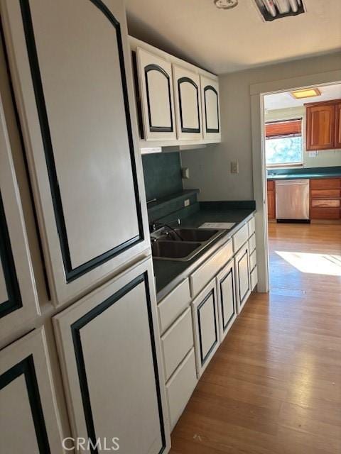 kitchen with sink, white cabinetry, dishwasher, and light hardwood / wood-style flooring