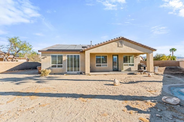 rear view of house with solar panels and a patio