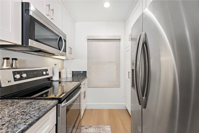 240 Moss St Unit 4, Laguna Beach, CA 92651 - kitchen with appliances with stainless steel finishes, light wood-style flooring, white cabinets, dark stone countertops, and baseboards