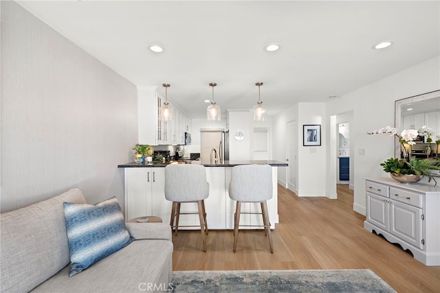 240 Moss St Unit 4, Laguna Beach, CA 92651 - kitchen with white cabinets, a peninsula, light wood-style floors, a breakfast bar, and recessed lighting