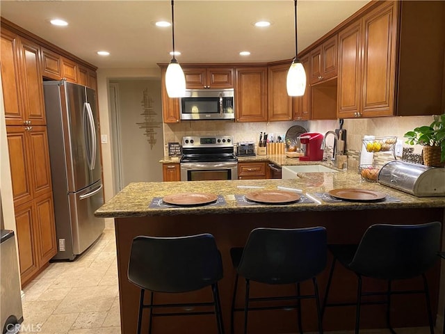 kitchen with kitchen peninsula, a breakfast bar, stainless steel appliances, sink, and hanging light fixtures