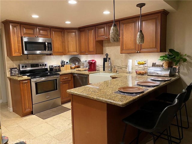 kitchen featuring sink, a breakfast bar area, light stone counters, kitchen peninsula, and stainless steel appliances