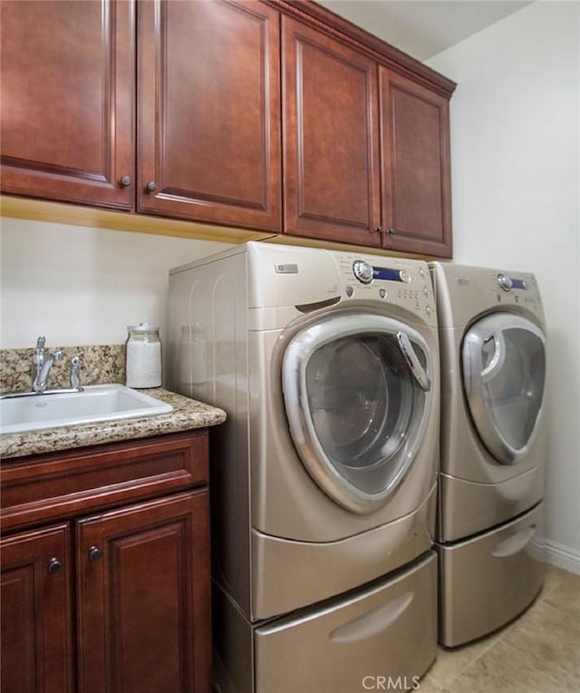 clothes washing area with tile patterned flooring, sink, washing machine and clothes dryer, and cabinets