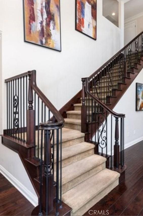 stairway with wood-type flooring and ornamental molding