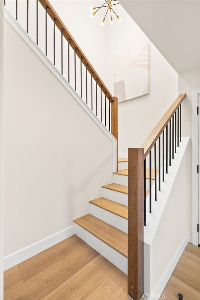 stairway with a chandelier and wood-type flooring