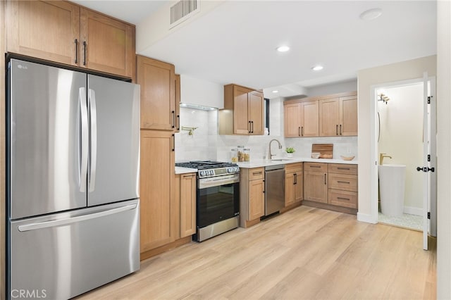 kitchen featuring sink, light wood-type flooring, stainless steel appliances, and tasteful backsplash