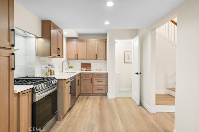 kitchen with sink, appliances with stainless steel finishes, light hardwood / wood-style flooring, and tasteful backsplash