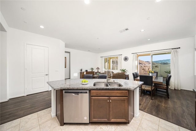 kitchen with light tile patterned floors, an island with sink, stainless steel dishwasher, and sink