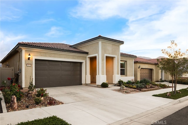 mediterranean / spanish house featuring a tiled roof, concrete driveway, an attached garage, and stucco siding