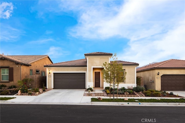 mediterranean / spanish-style home featuring driveway, an attached garage, a tiled roof, and stucco siding