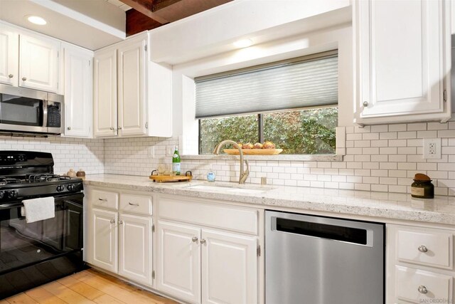 kitchen featuring appliances with stainless steel finishes, tasteful backsplash, white cabinets, and sink