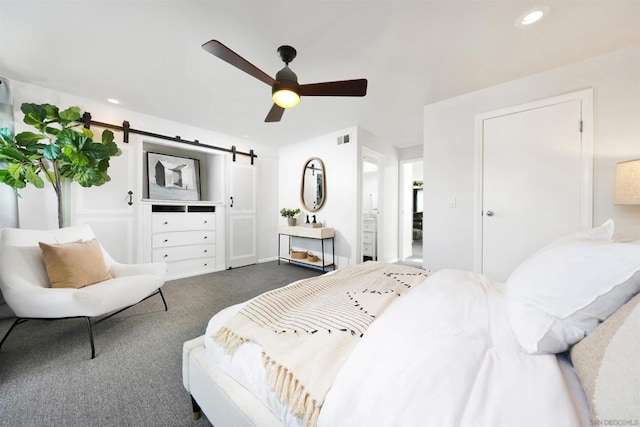 carpeted bedroom featuring ceiling fan and a barn door