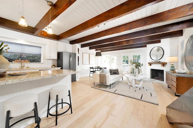 living room with light wood-type flooring, wooden ceiling, beamed ceiling, and sink