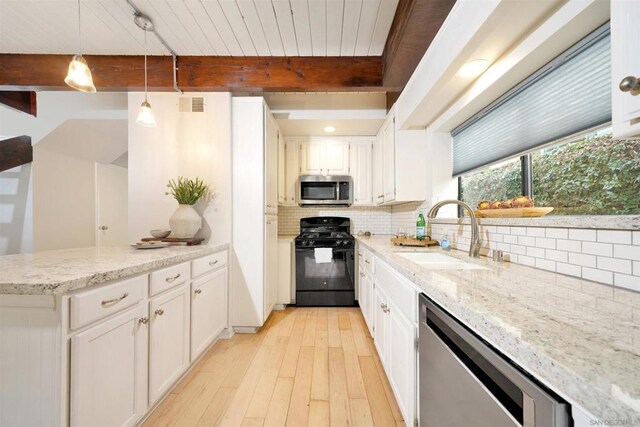 kitchen featuring hanging light fixtures, beam ceiling, white cabinetry, appliances with stainless steel finishes, and sink