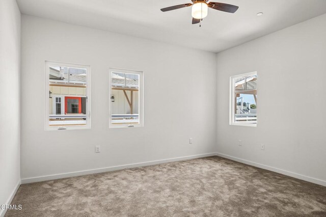 carpeted empty room featuring ceiling fan and a healthy amount of sunlight