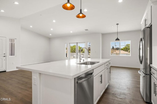 kitchen with white cabinetry, stainless steel appliances, sink, hanging light fixtures, and a center island with sink