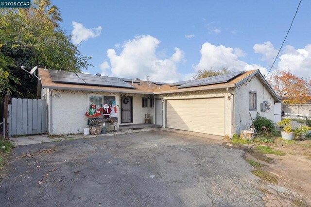 single story home featuring solar panels and a garage