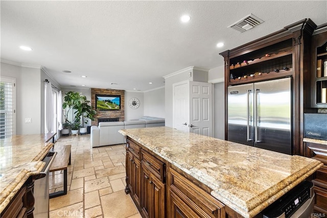 kitchen with light stone countertops, crown molding, stainless steel appliances, and a kitchen island