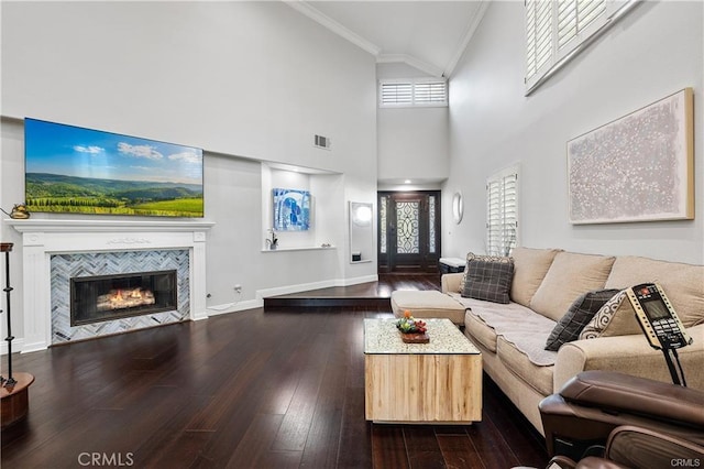 living room with a high ceiling, ornamental molding, a fireplace, and dark hardwood / wood-style floors