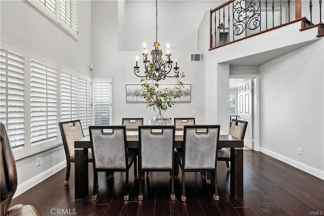 dining area with a towering ceiling, dark hardwood / wood-style floors, and a chandelier