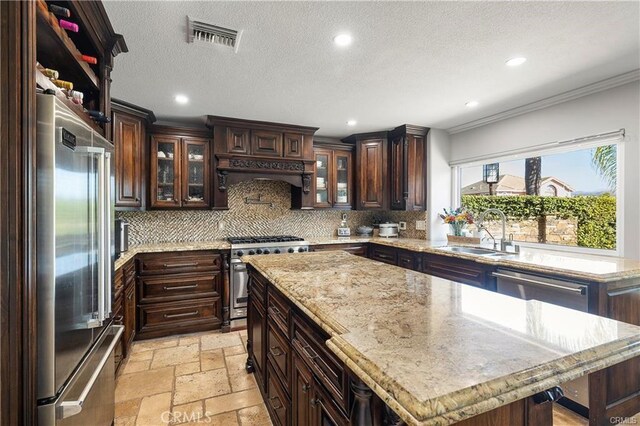 kitchen with a kitchen island, decorative backsplash, sink, dark brown cabinetry, and high quality appliances