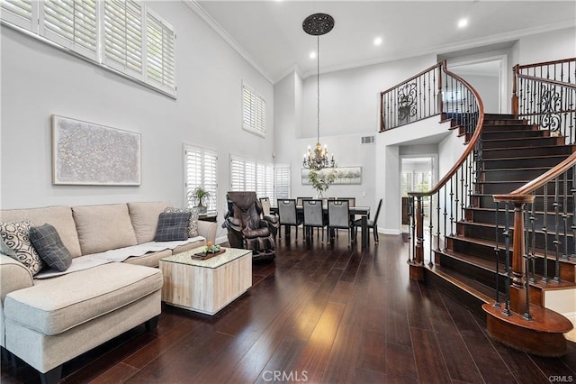 living room with dark hardwood / wood-style floors, an inviting chandelier, a high ceiling, crown molding, and plenty of natural light