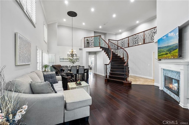 living room featuring hardwood / wood-style floors, a high end fireplace, ornamental molding, and a high ceiling