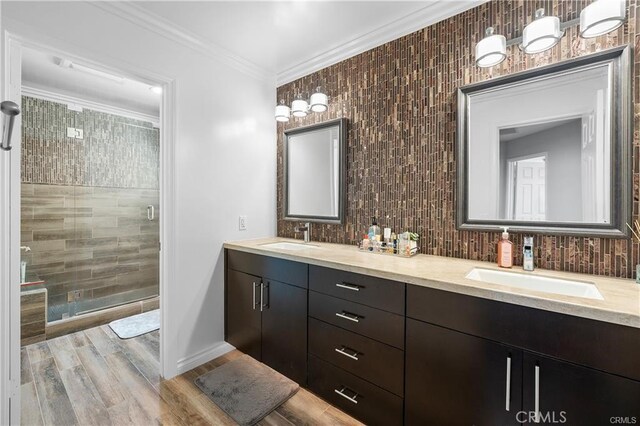 bathroom with hardwood / wood-style flooring, a shower with shower door, vanity, and ornamental molding