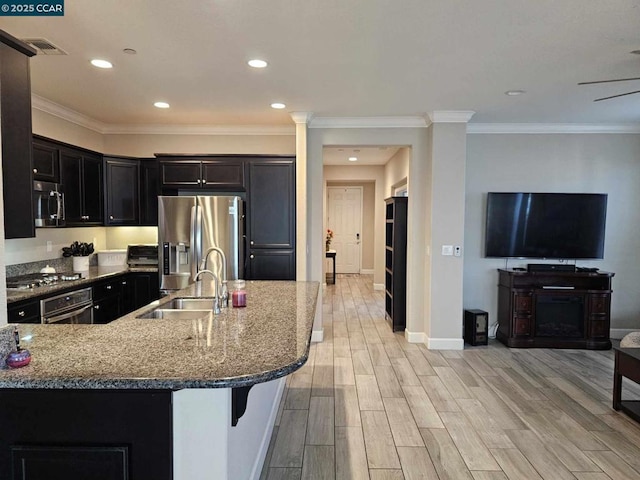 kitchen featuring a breakfast bar area, appliances with stainless steel finishes, light stone countertops, crown molding, and sink