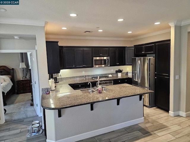 kitchen with a breakfast bar, kitchen peninsula, sink, crown molding, and appliances with stainless steel finishes