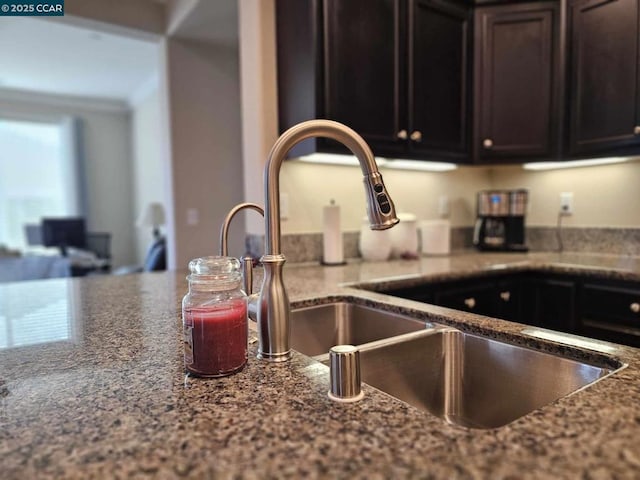 kitchen with sink, dark brown cabinets, and dark stone counters