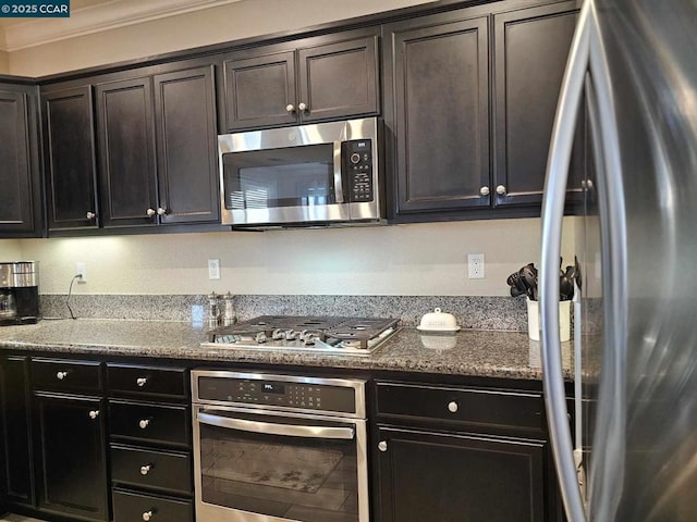 kitchen featuring dark brown cabinets, stainless steel appliances, dark stone countertops, and ornamental molding