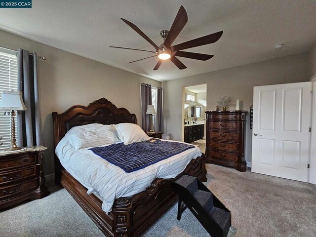 bedroom with ceiling fan, light colored carpet, and ensuite bath