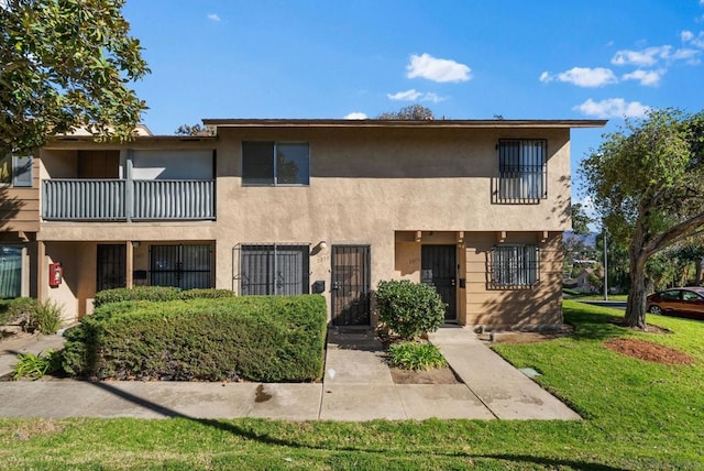 view of property featuring a balcony and a front yard