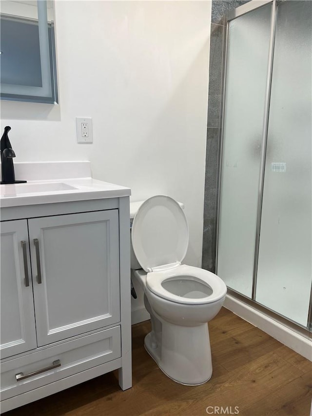 bathroom featuring vanity, hardwood / wood-style flooring, toilet, and an enclosed shower