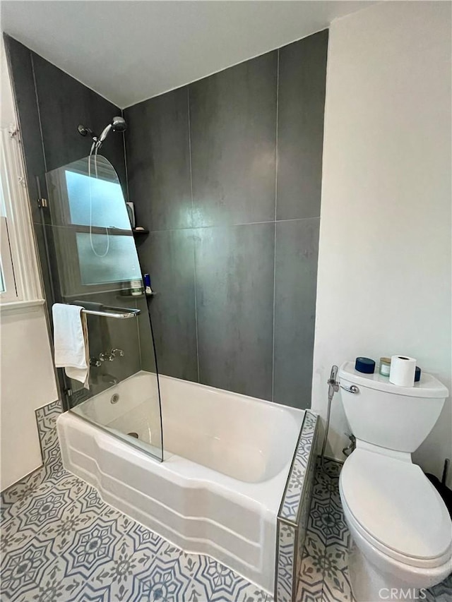 bathroom featuring tile patterned flooring, toilet, and tiled shower / bath