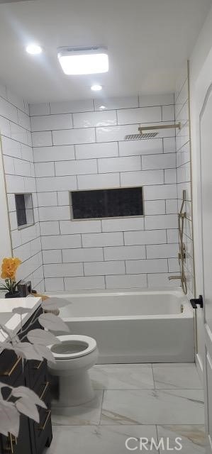 bathroom featuring toilet and tiled shower / bath