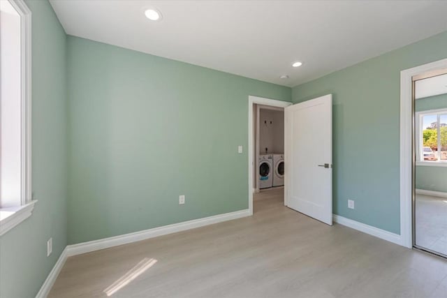 unfurnished bedroom featuring separate washer and dryer and light hardwood / wood-style floors