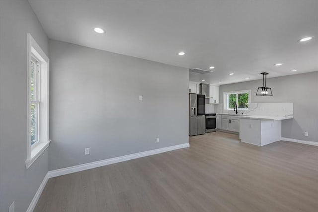 kitchen featuring kitchen peninsula, stainless steel appliances, tasteful backsplash, hanging light fixtures, and white cabinets