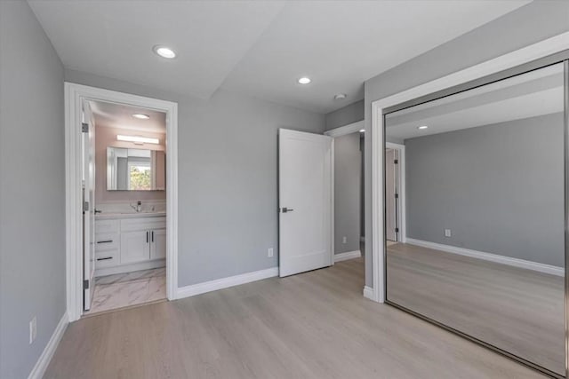 unfurnished bedroom featuring light wood-type flooring, connected bathroom, and sink