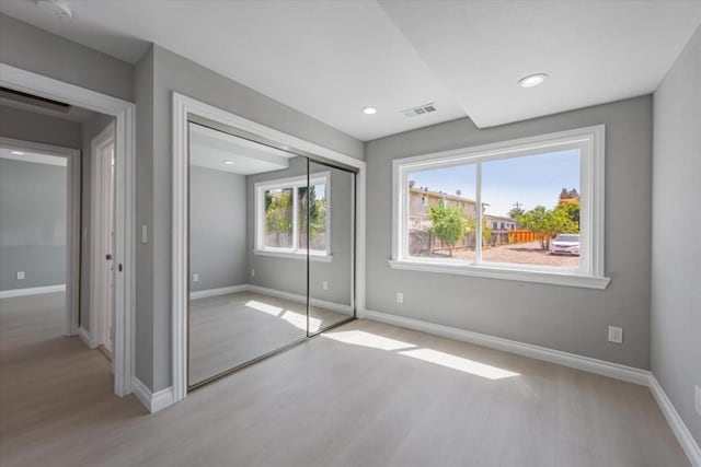 unfurnished bedroom with a closet and light hardwood / wood-style flooring