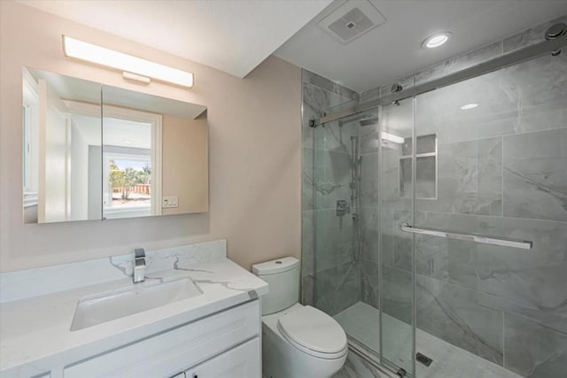 bathroom featuring a shower with shower door, toilet, and vanity