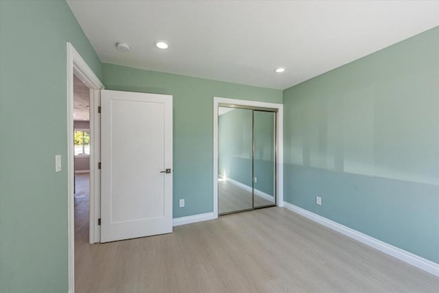 unfurnished bedroom featuring a closet and light wood-type flooring