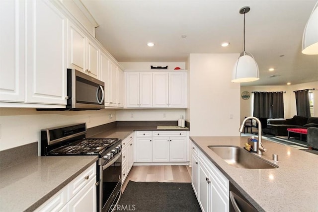 kitchen featuring light stone counters, sink, white cabinets, and appliances with stainless steel finishes