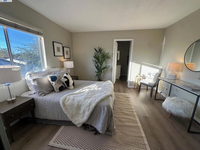 bedroom featuring dark wood-type flooring and ensuite bath