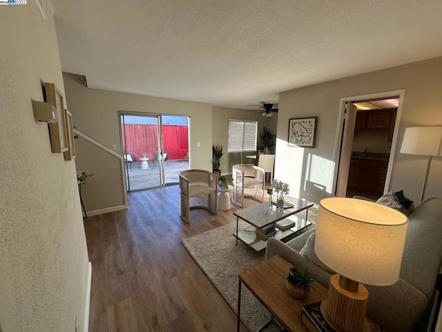 living room with ceiling fan, a textured ceiling, and wood-type flooring