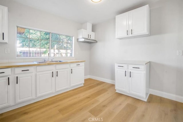 kitchen featuring light wood-type flooring, white cabinetry, and sink